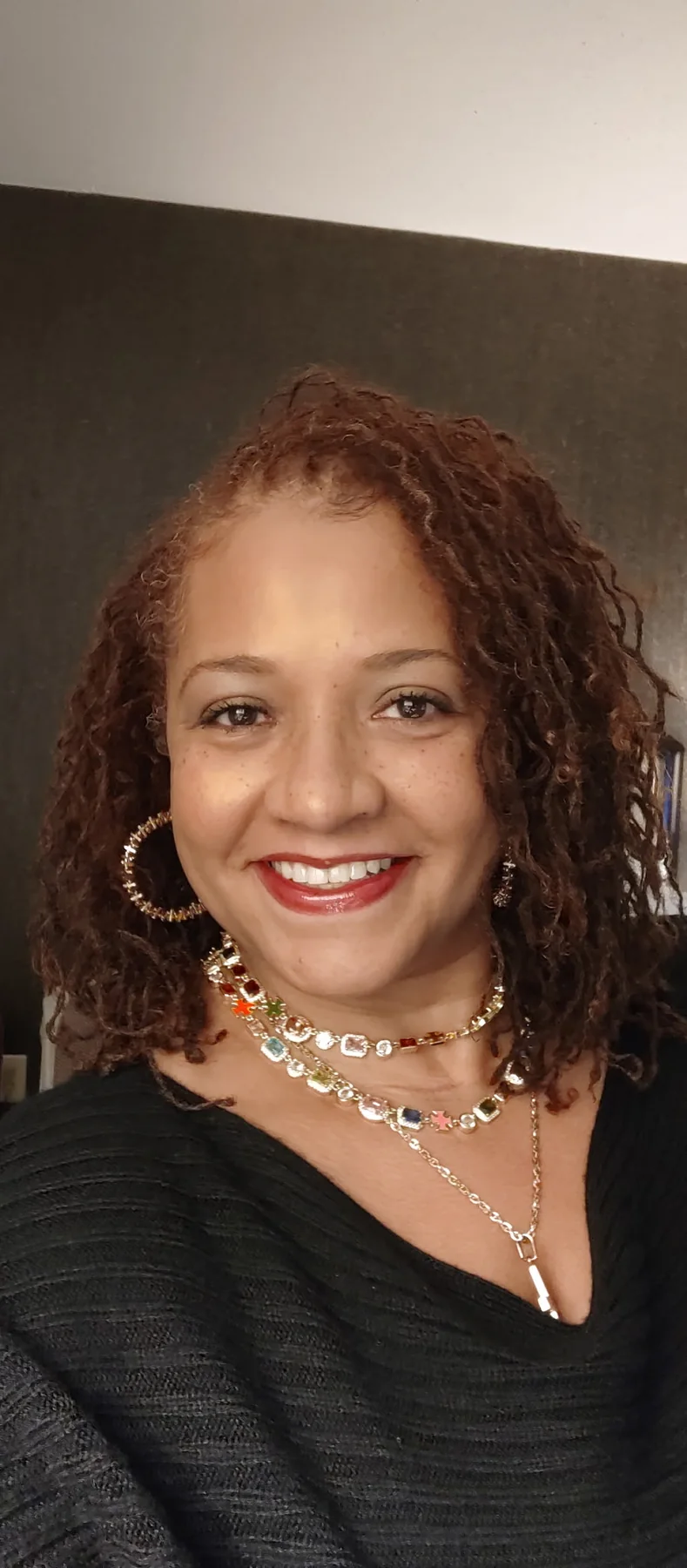 Atoya BFabulus Jones smiling in a polished black top and gold jewelry.