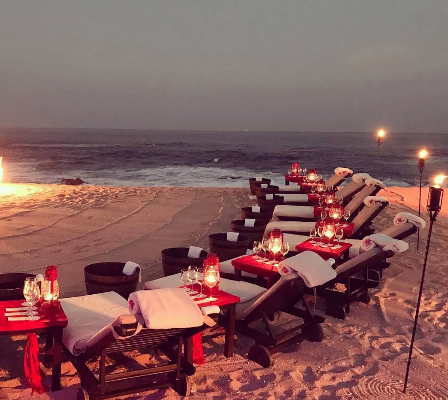 Luxury beachside dinner and lounge setup at sunset.