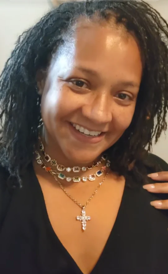 Atoya smiling in a beauty and confidence moment with gold jewelry.