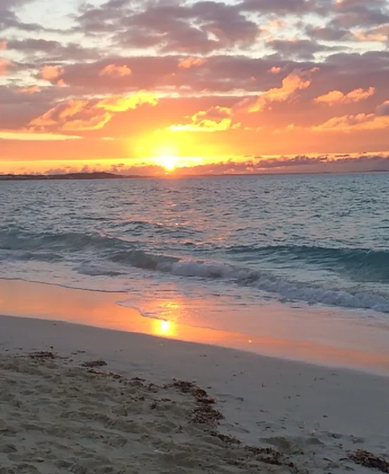 Warm sunset over the ocean and beach for soft destination reset storytelling.