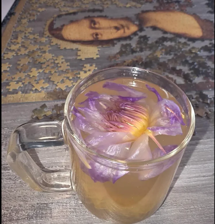 Clear tea mug with flower petals over a calming puzzle table.