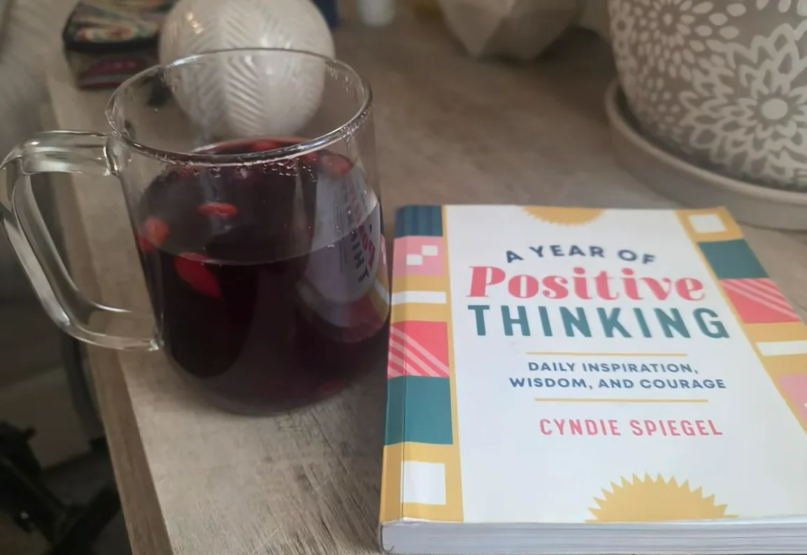 Tea beside a positive thinking book for a reflective self-care ritual.
